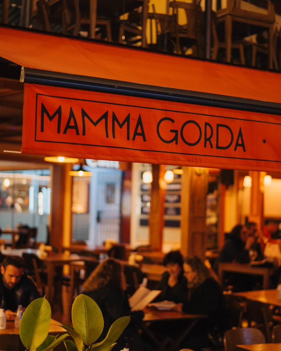 Fachada do Mamma Gorda na Vila Capivari, com o letreiro do restaurante e o salão ao fundo.